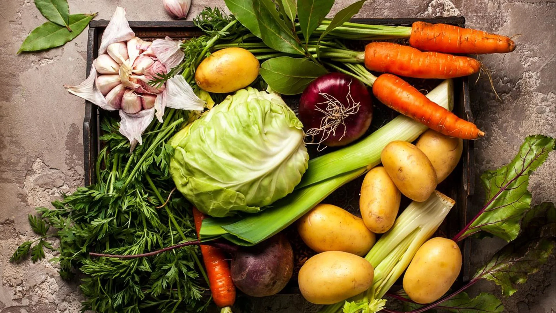 Una cassetta fotografata dall'alto con verdure colorate come cavoli, carote e patate