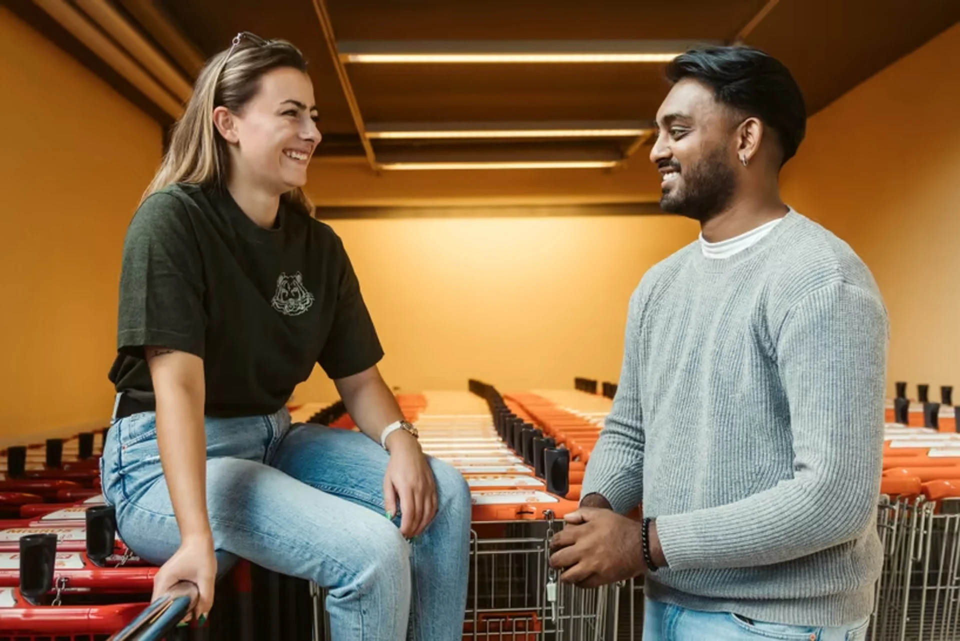 Deux apprentis discutent près des caddies dans un magasin Migros