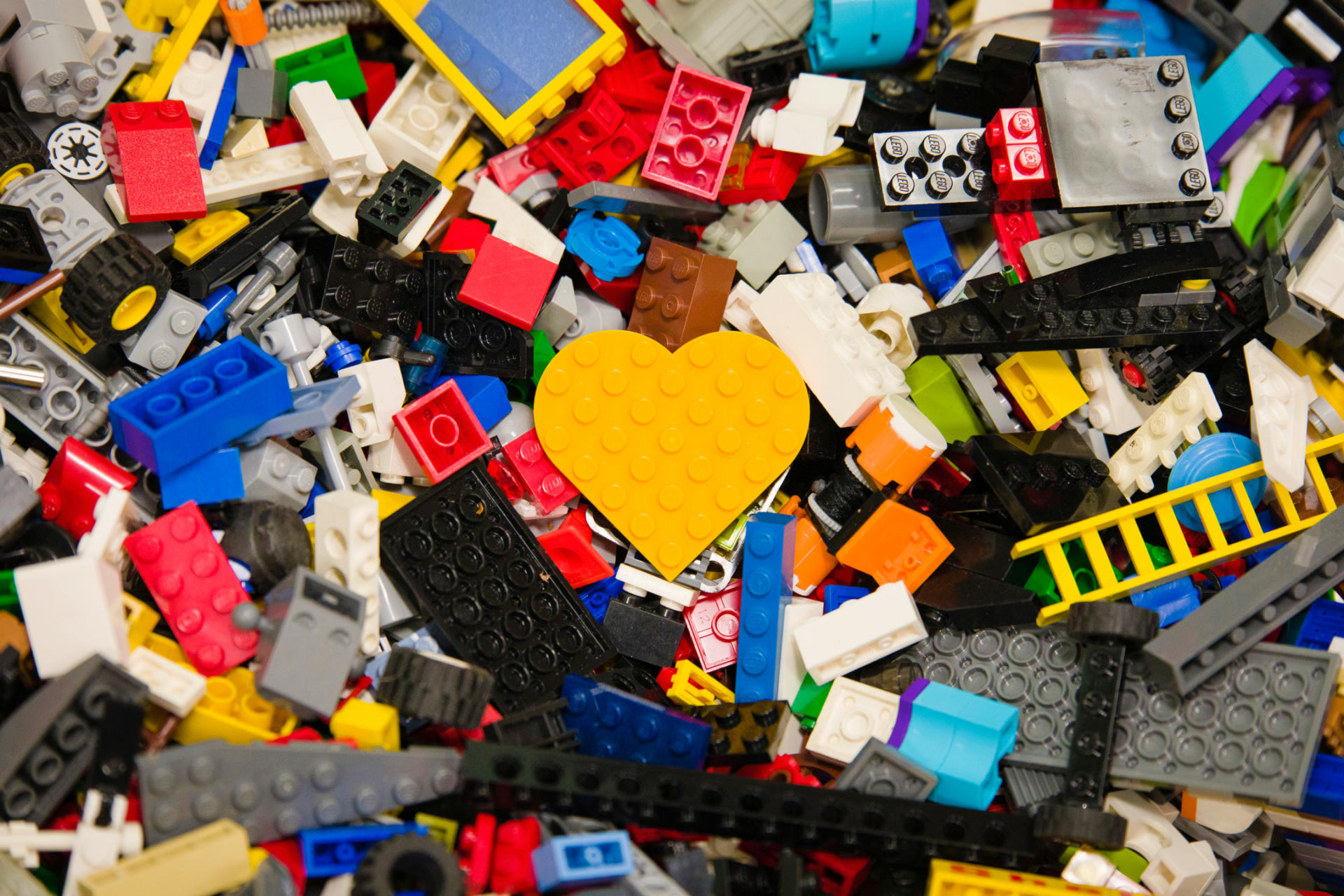 Un mattoncino Lego a forma di cuore in mezzo a tanti altri mattoncini Lego