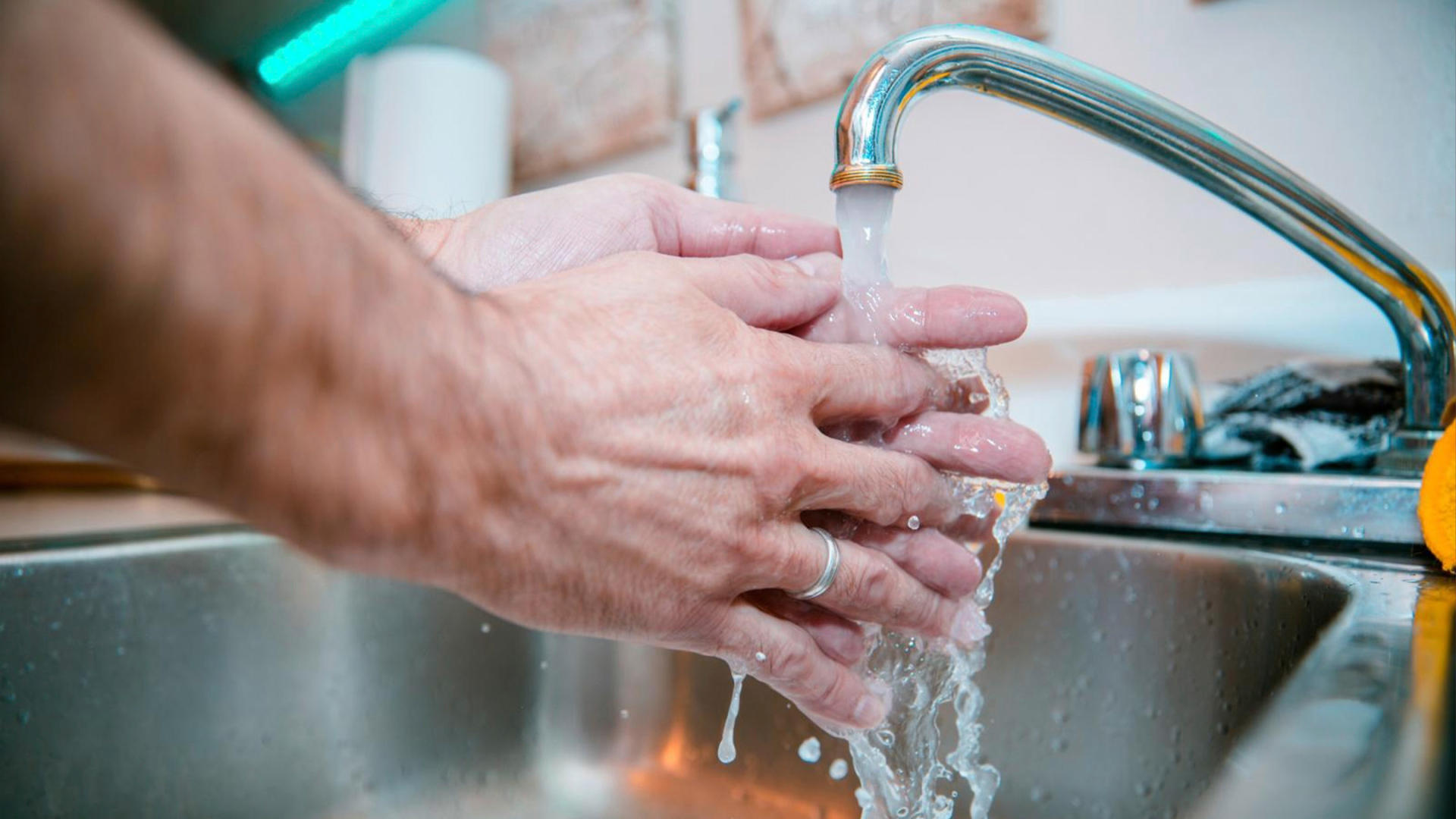 Una persona si lava le mani sotto l'acqua di un rubinetto
