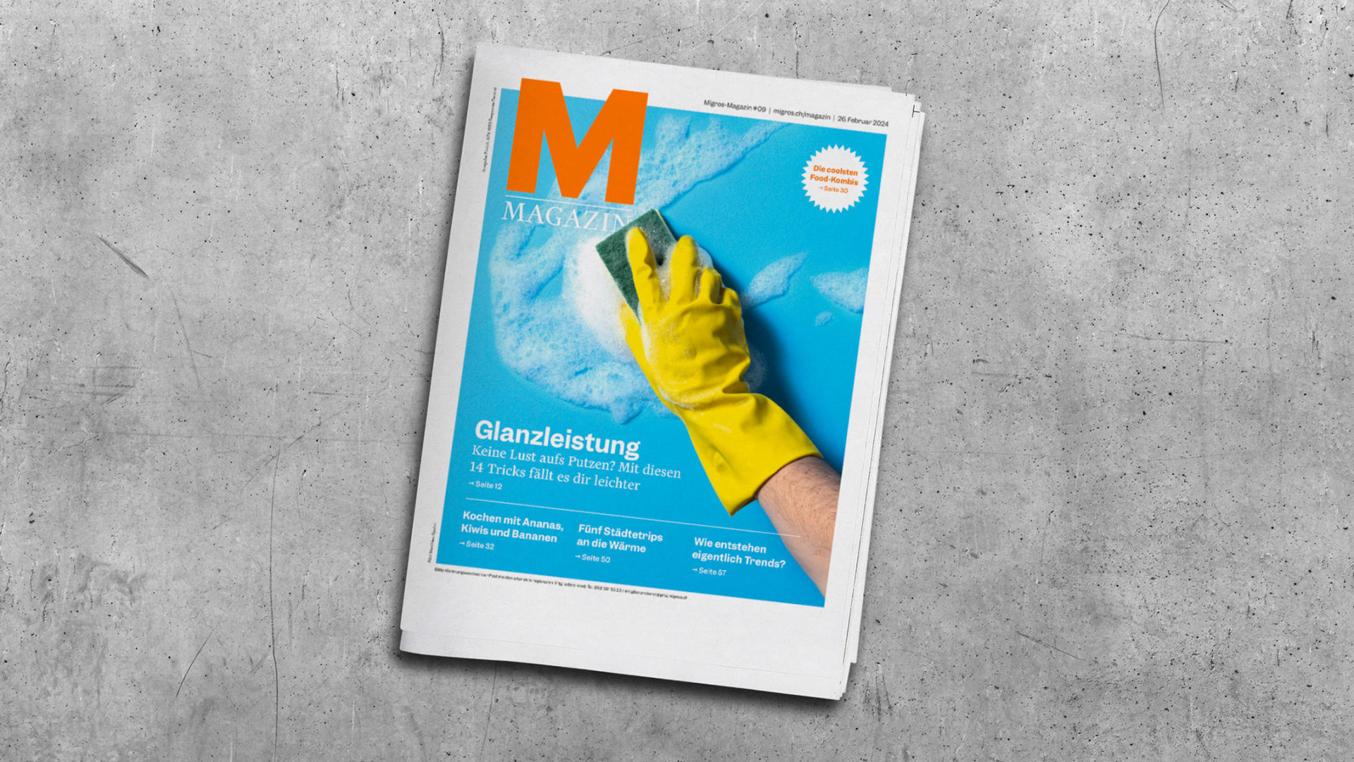 An issue of Migros magazine on a grey table.