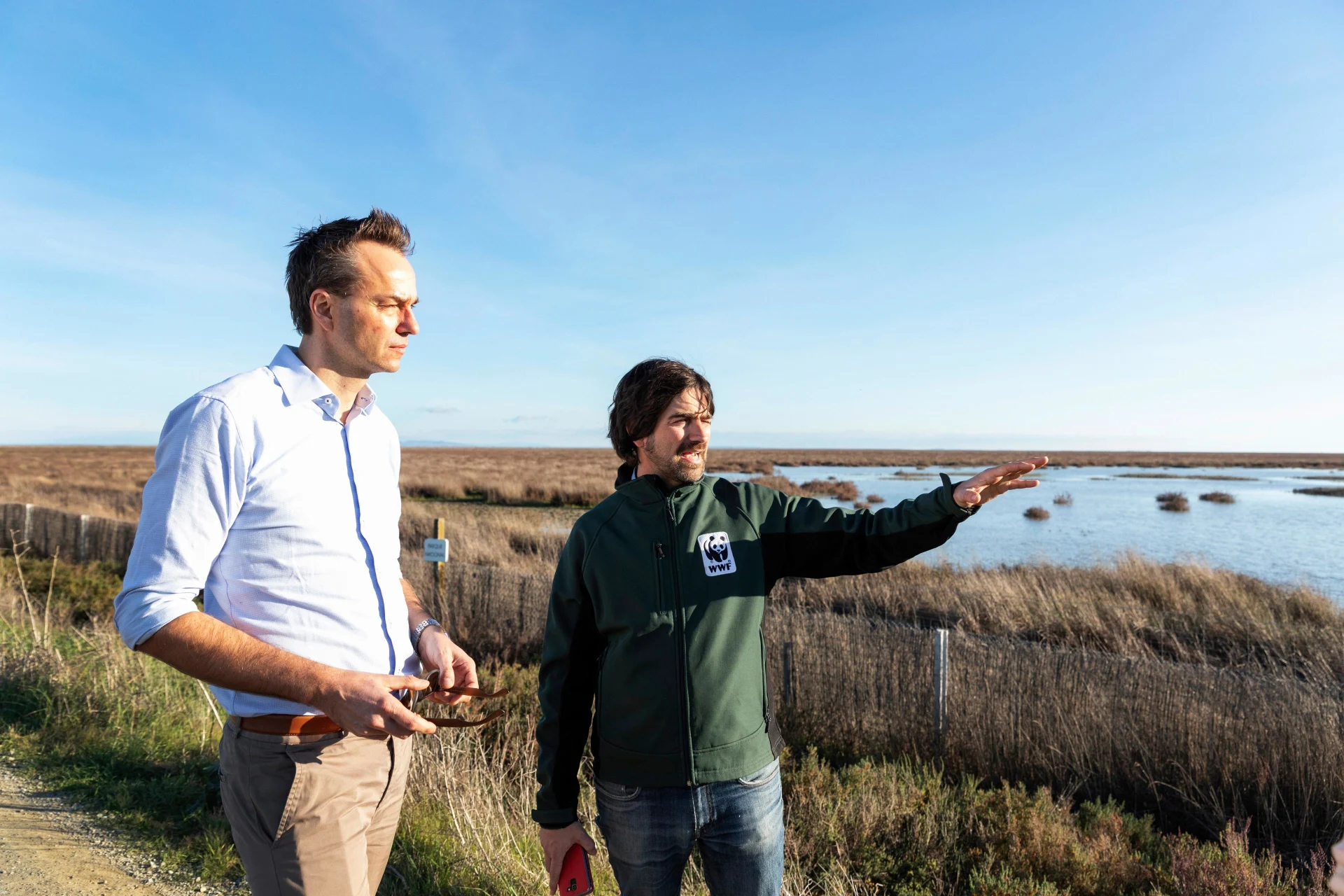 Two people stand in a nature reserve and look into the distance.