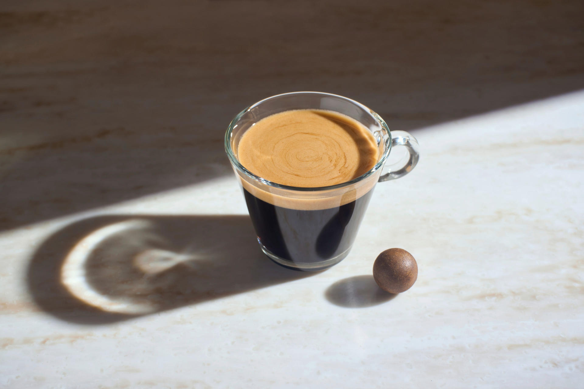 A cup of espresso next to a coffee ball.