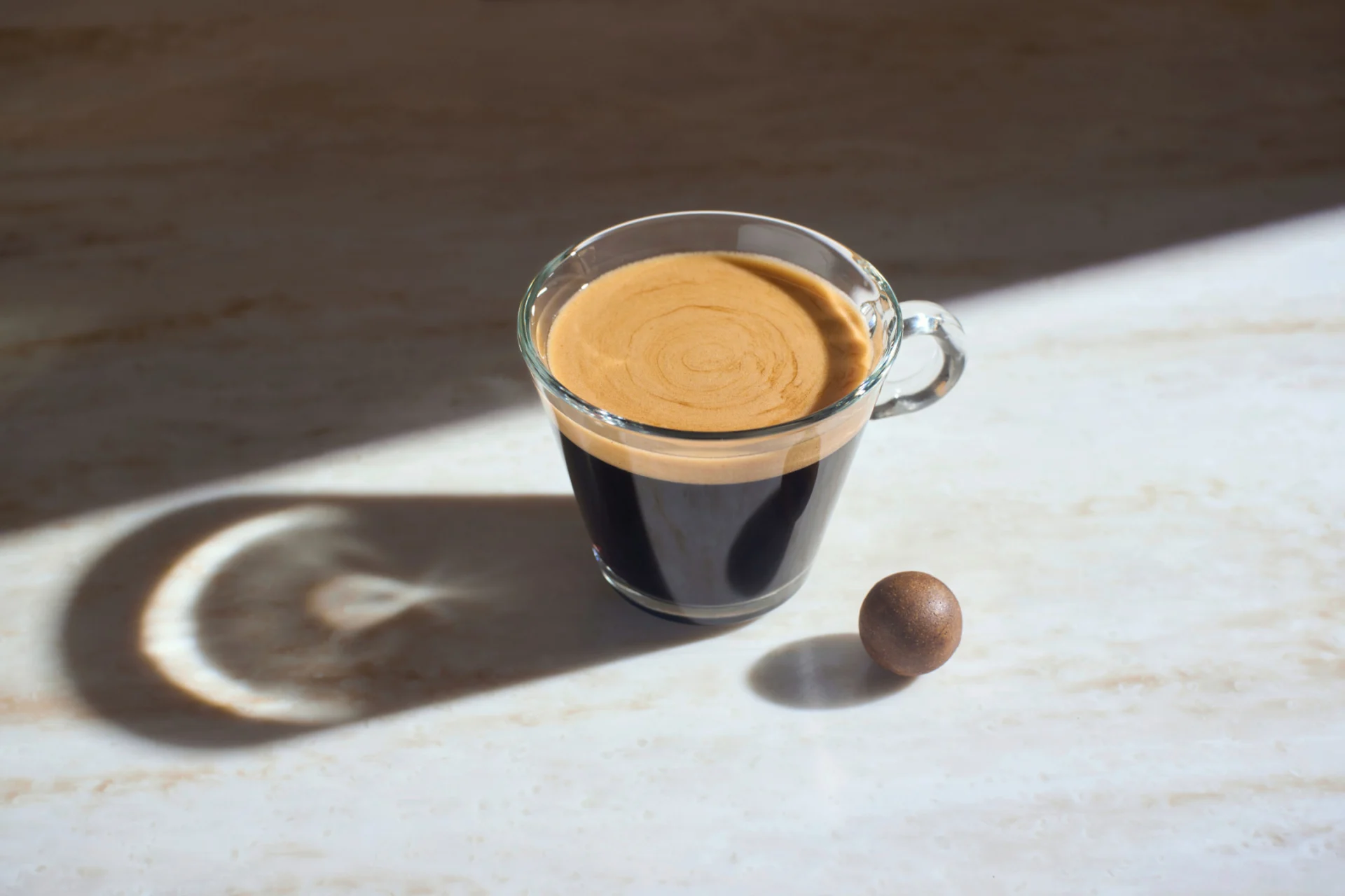 Una tazzina di espresso con accanto una sfera di caffè.