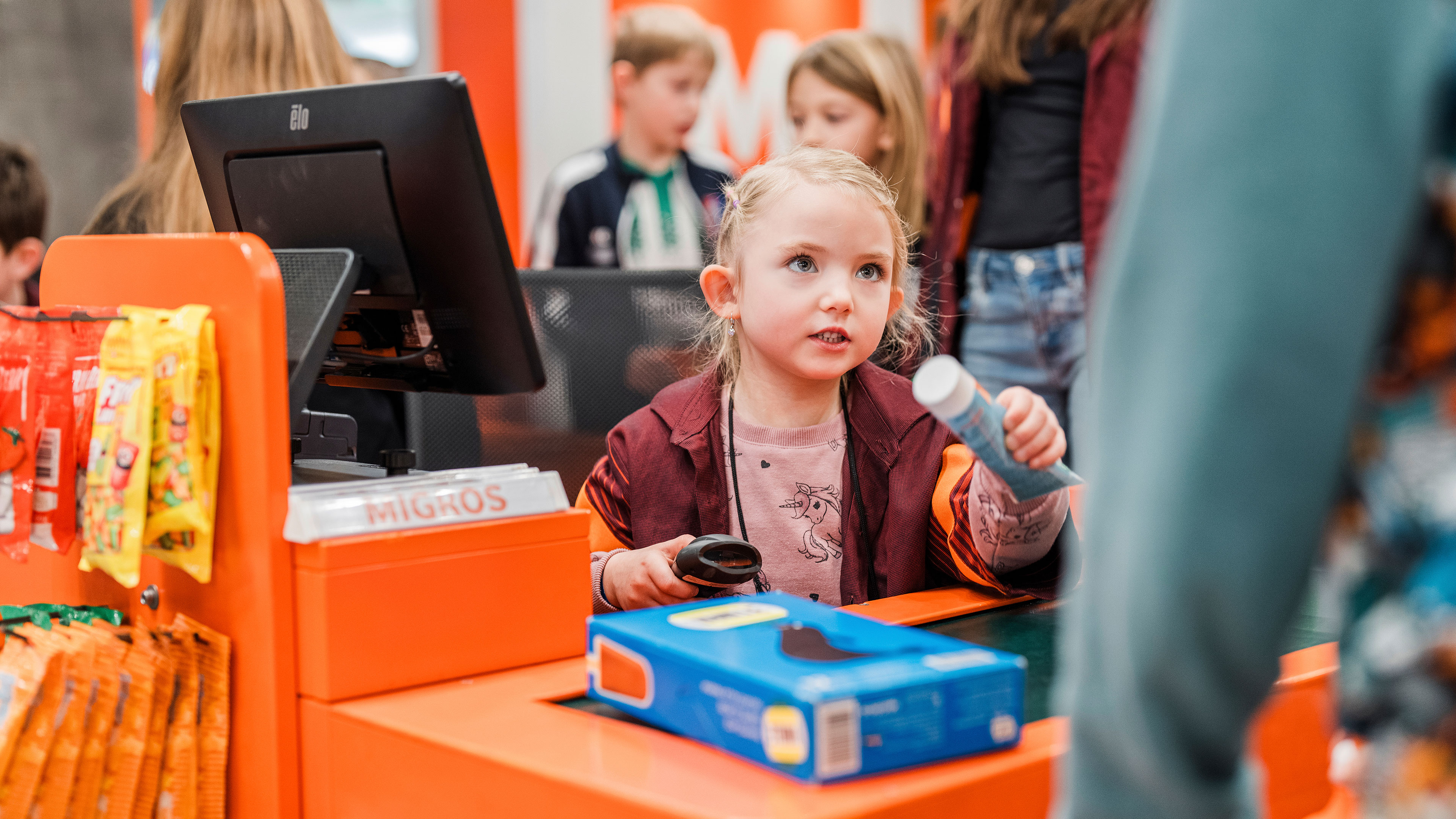 Ein Mädchen sitzt an der Kasse und scannt Produkte