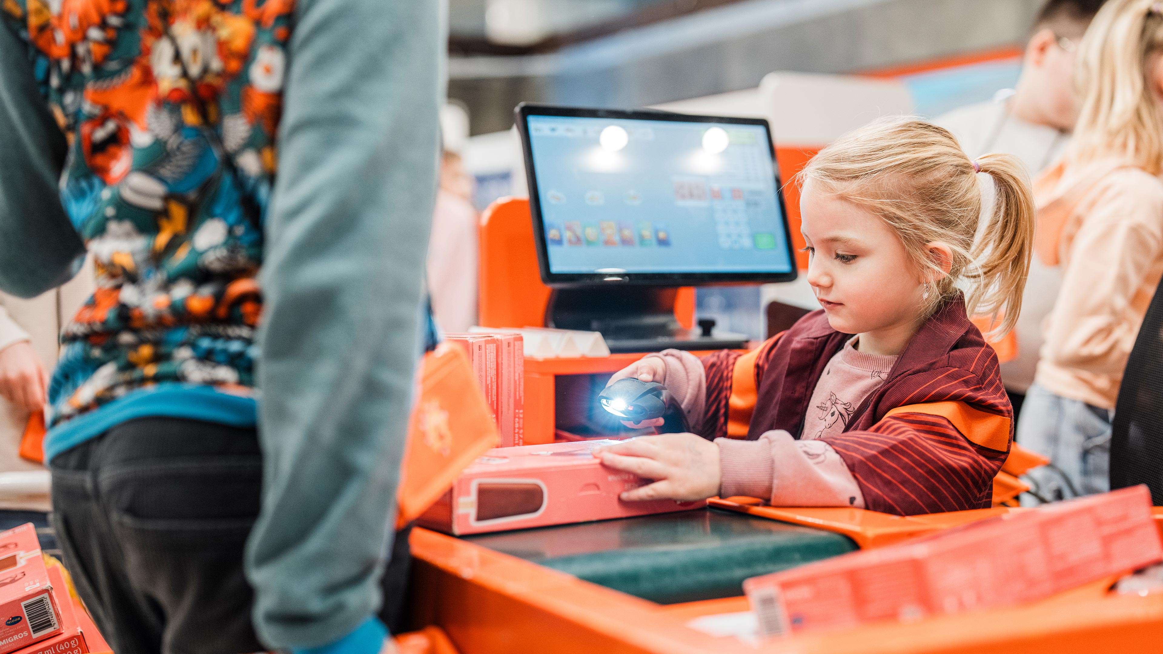 Una ragazza è seduta alla cassa e sta scansionando prodotti
