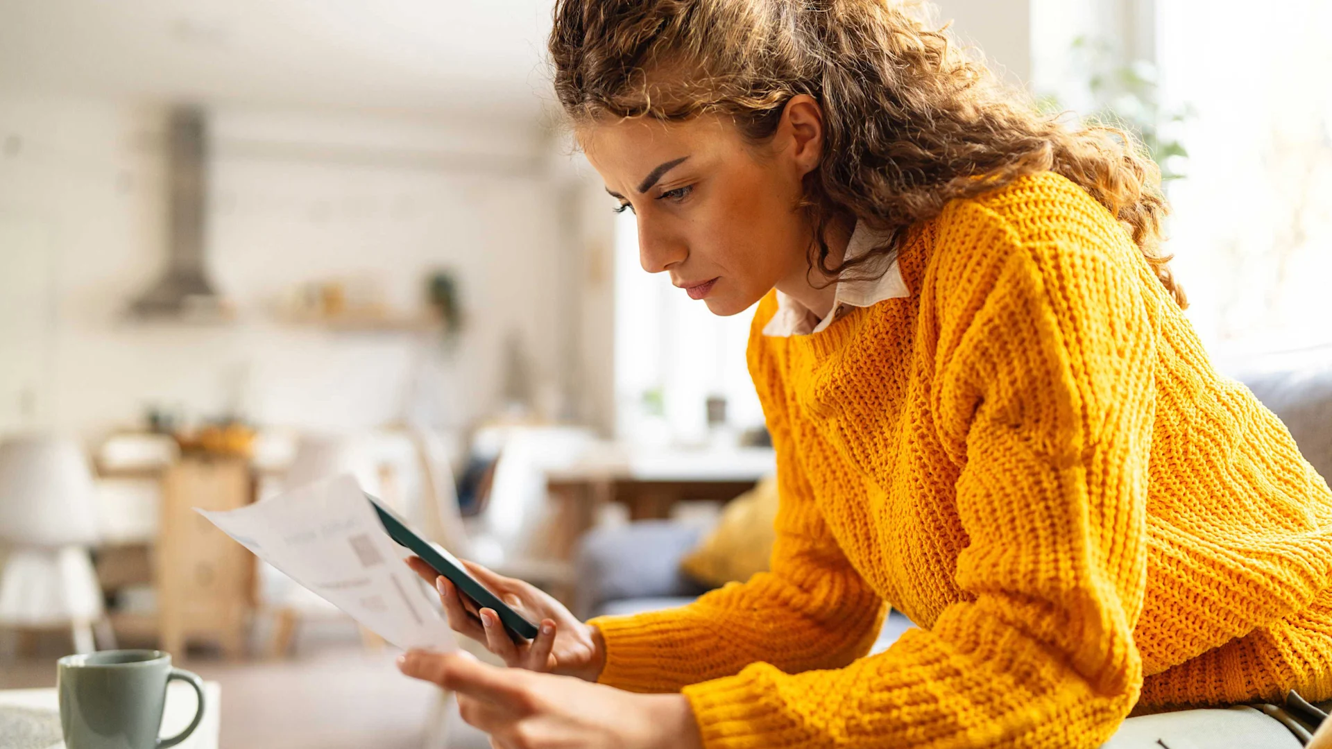 Una donna controlla l'estratto conto ed esegue calcoli sul suo cellulare.