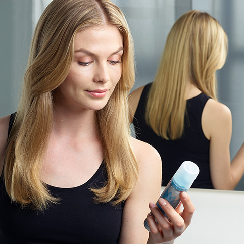 Woman with hair loss looking at Regaine® foam