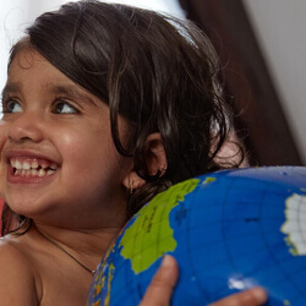 toddler holding globe in bath