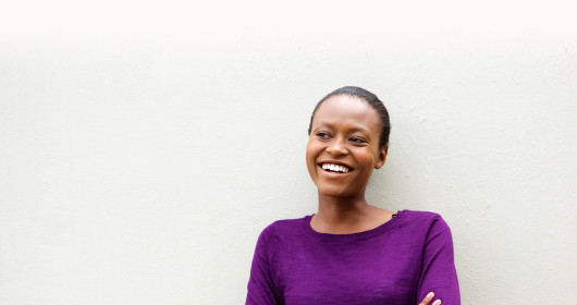 African woman smiling while standing with her arms crossed