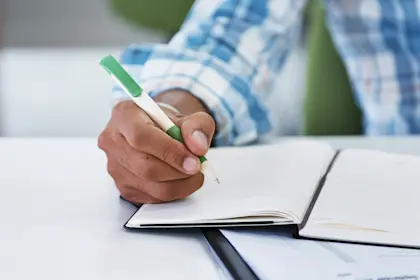 Man sitting at a desk writing in a notebook