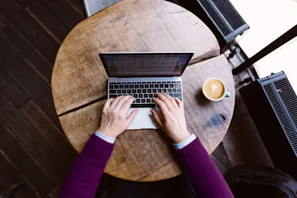 personal perspective view of a man working on a laptop in a coffee shop