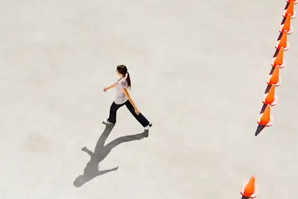 Woman walking through opening in row of traffic cones