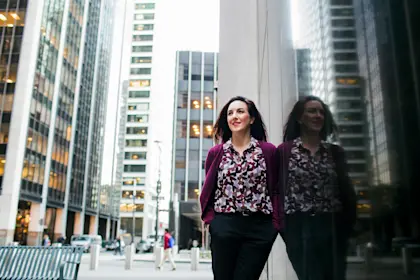 Low angle view of smiling businesswoman standing by glass window in city