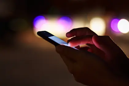 Close up photo of hand using a cell phone at night 