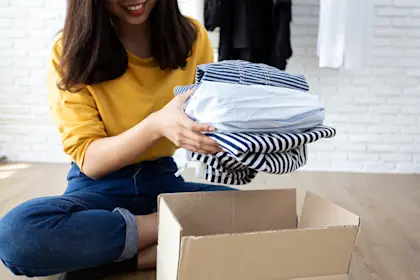 Woman holding Clothes with Donate Box In her room