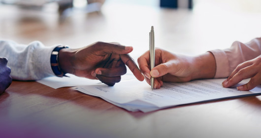 Two people reviewing and signing a contract
