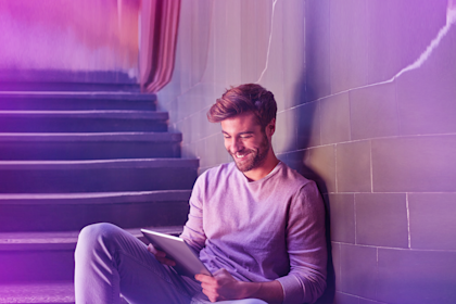 Smiling man using tablet PC while sitting on staircase