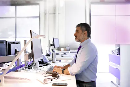 Man typing on computer at stand-up desk