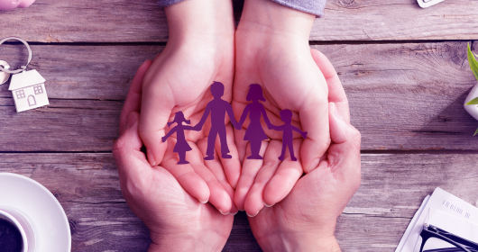 cuffed hands holding paper cutout of family