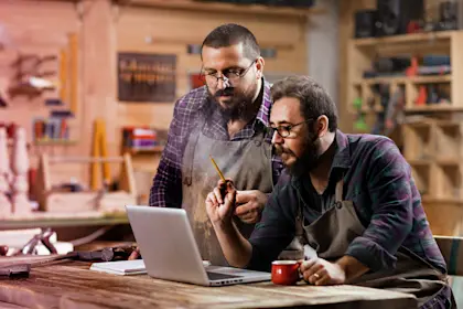 two male workers on a laptop