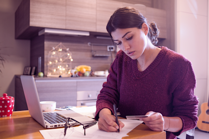 Woman sitting at table working with open laptop next to her