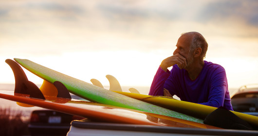 Senior man near the beach with surfboards by car 