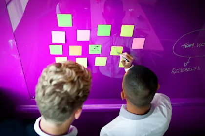 two young business men write on sticky notes