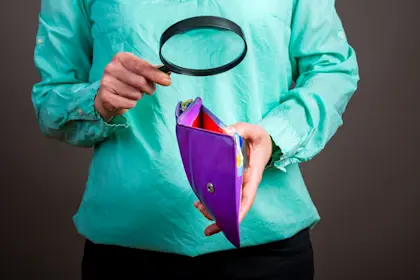 woman looking in empty wallet with magnifying glass