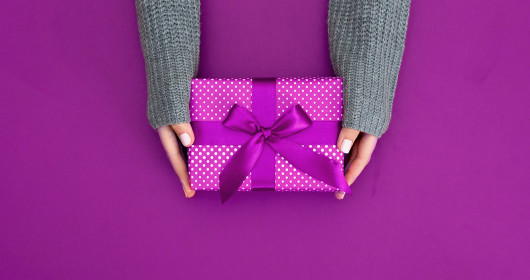 gift in female hands on a colored background