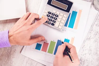 man's hands holding a pen and using a calculator 