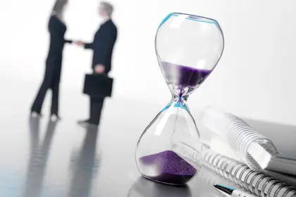 Giant hourglass with man and woman shaking hands in background