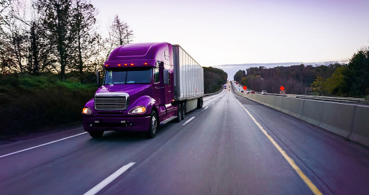 18 wheeler purple semi truck on highway at dusk