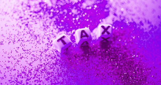 purple glitter and dice that spell TAX