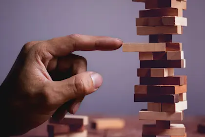 Closeup of a hand pulling out a wooden block in a tower.