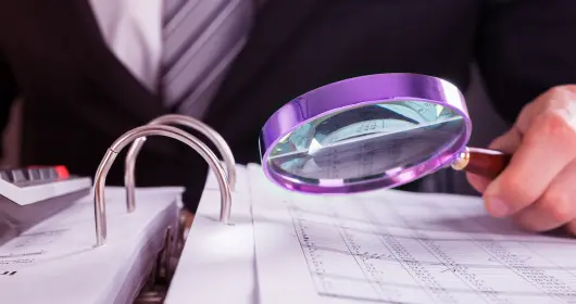 Businessman examining an invoice with a magnifying glass