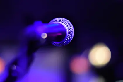 Close up photo of microphone against illuminated stage lights