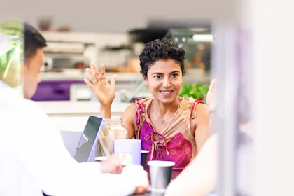 Indian woman smiling with hand raised during casual business meeting