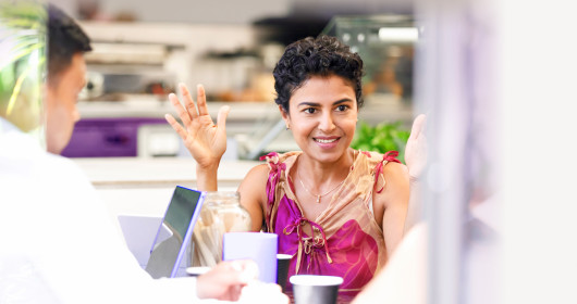 Indian woman smiling with hand raised during casual business meeting