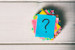 Question mark written on a stack of colored papers