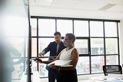 Two business people looking at laptop in conference room