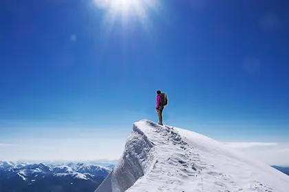 Person standing on top of snow covered mountain