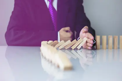 business man knocking over a row of dominoes
