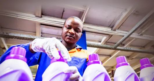 Worker closing detergent bottle at household factory