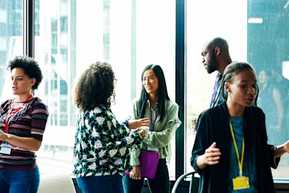 People standing in office talking front of glass windows