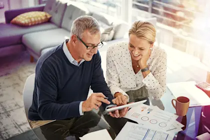 mature couple using a digital tablet while going through paperwork at home