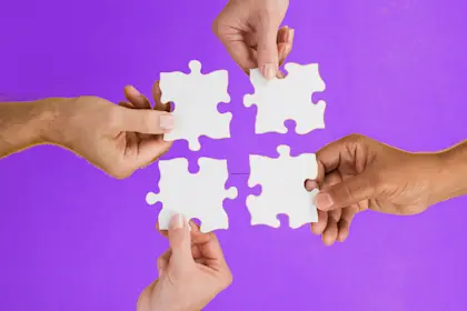 Close up of four hands holding puzzle pieces