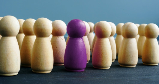 one purple wooden figures among others on a desk