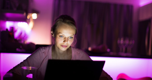 Woman's face illuminated from using laptop in a dark room