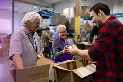 elderly volunteers filling donation boxes in a warehouse